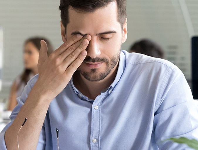 man rubs his eye